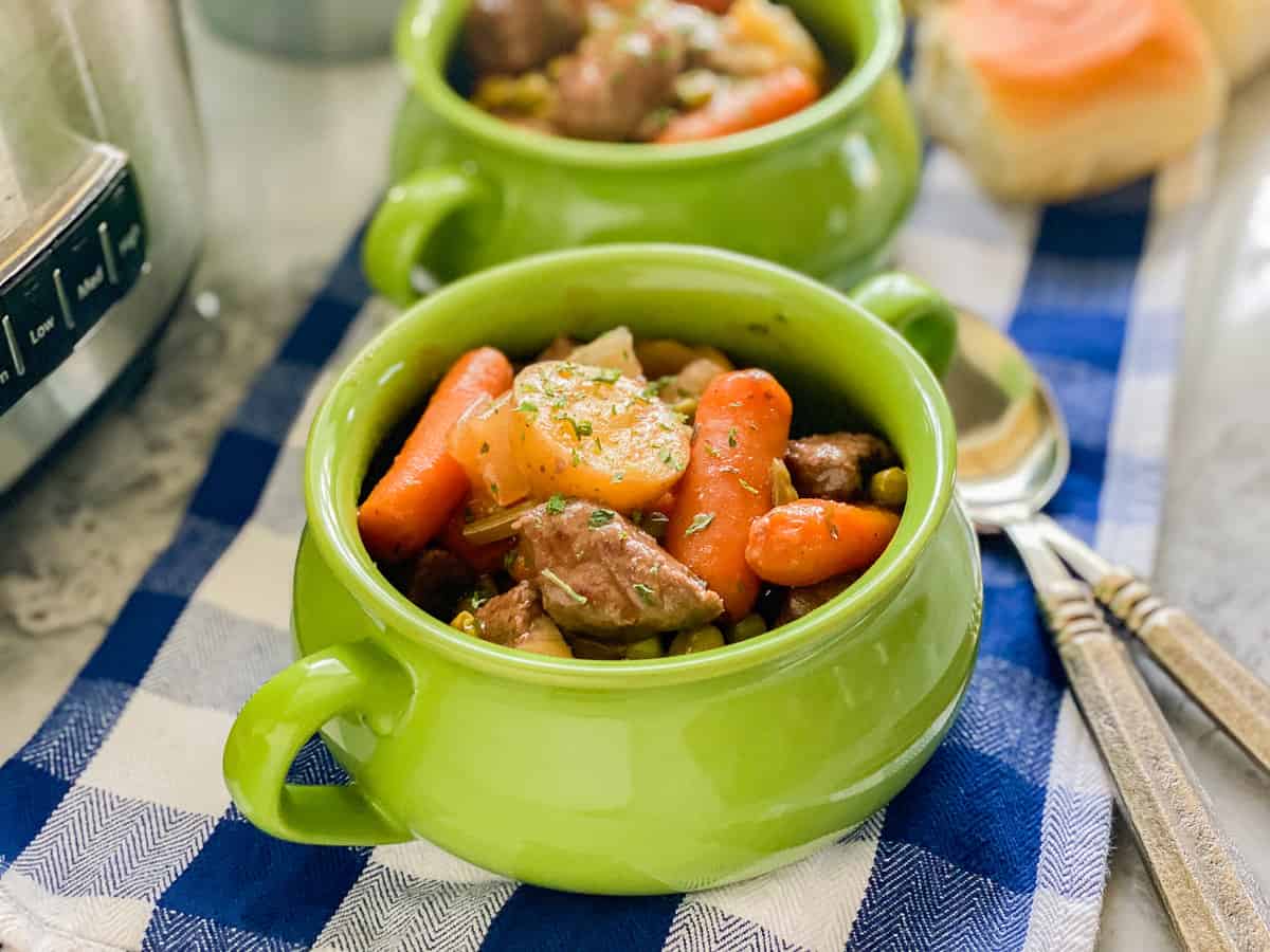 Close up of beef stew served in a mini green pot.