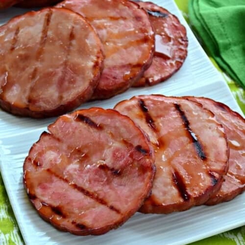 6 slices of ham steaks on a white platter with grill marks.