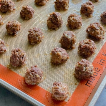 Round cooked meatballs on a baking tray.