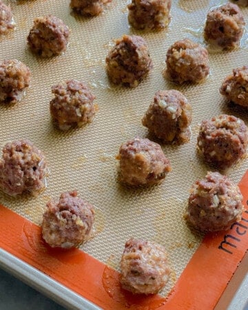 Round cooked meatballs on a baking tray.