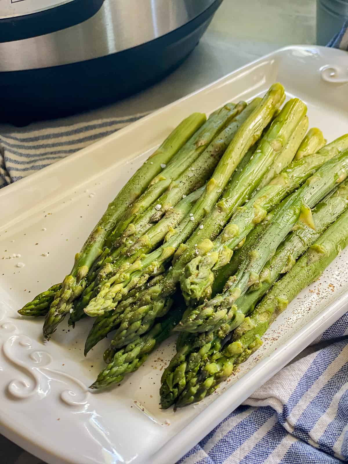 Close up photo cooked asparagus resting on a white ceramic serving dish.