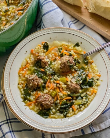 White bowl filled with meatball and pastaq soup with spoon in it.