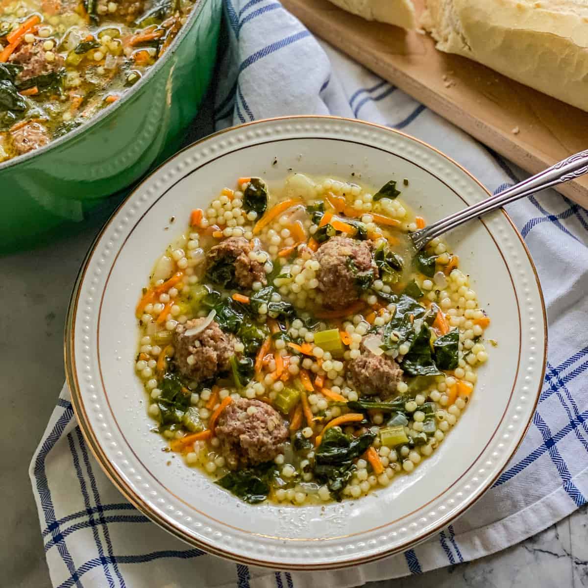 White bowl filled with meatball and pastaq soup with spoon in it.