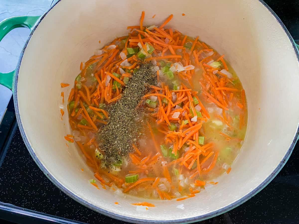 White pot filled with shredded carrots, diced onions, and diced celery.