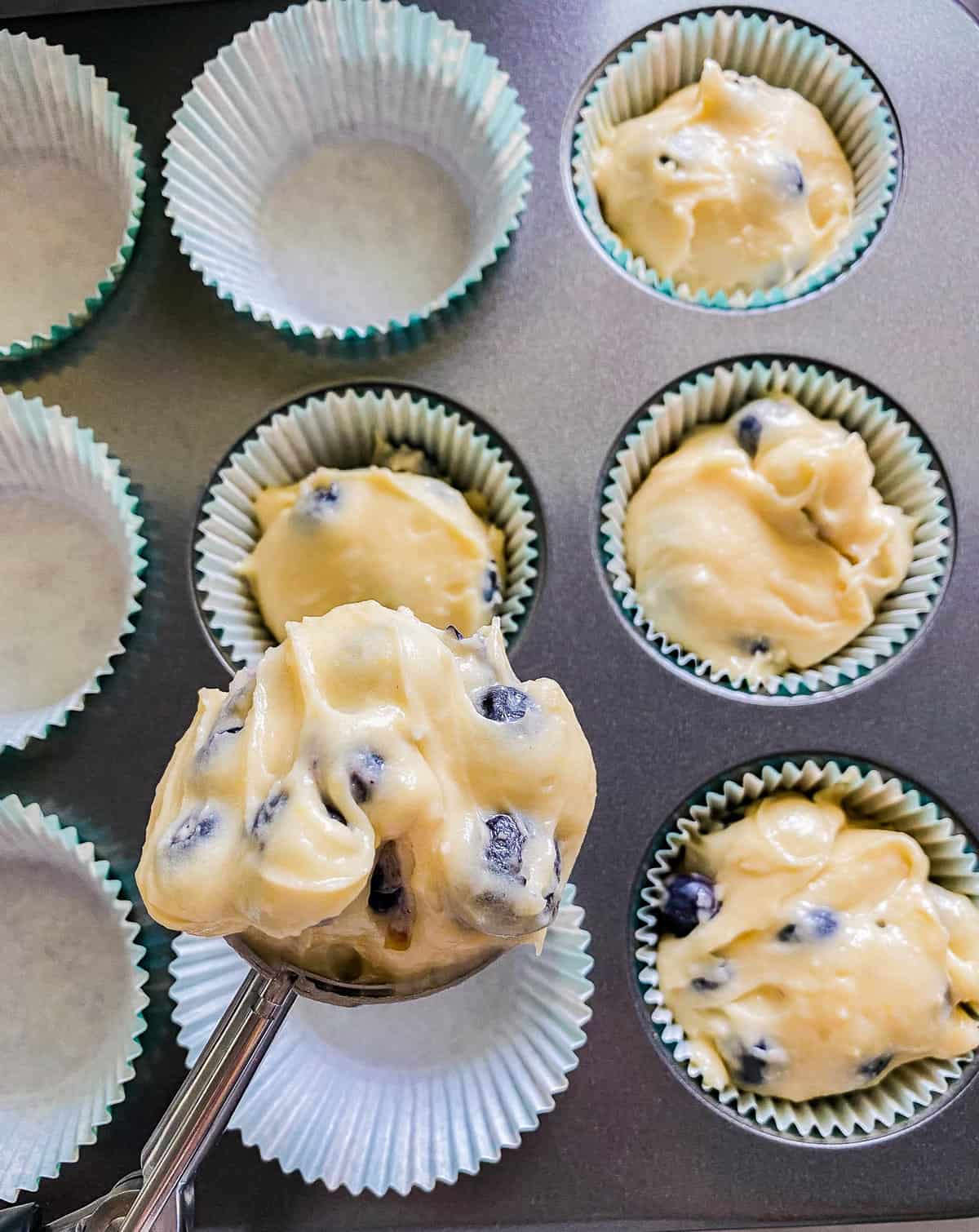 Scooping up the blueberry mix while the rest of the mixture is already resting in the muffin pan.