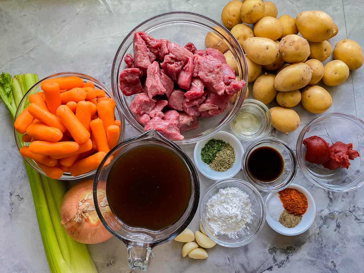 All the ingredients for the Slow Cooker Beef Stew spread across a white marble counter.