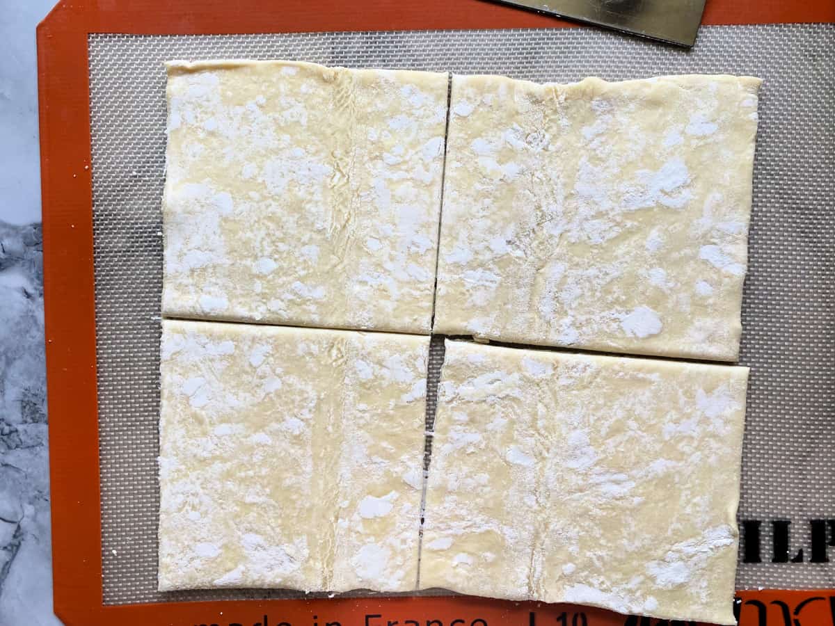 Four squares of puff pastry on a silpat mat.