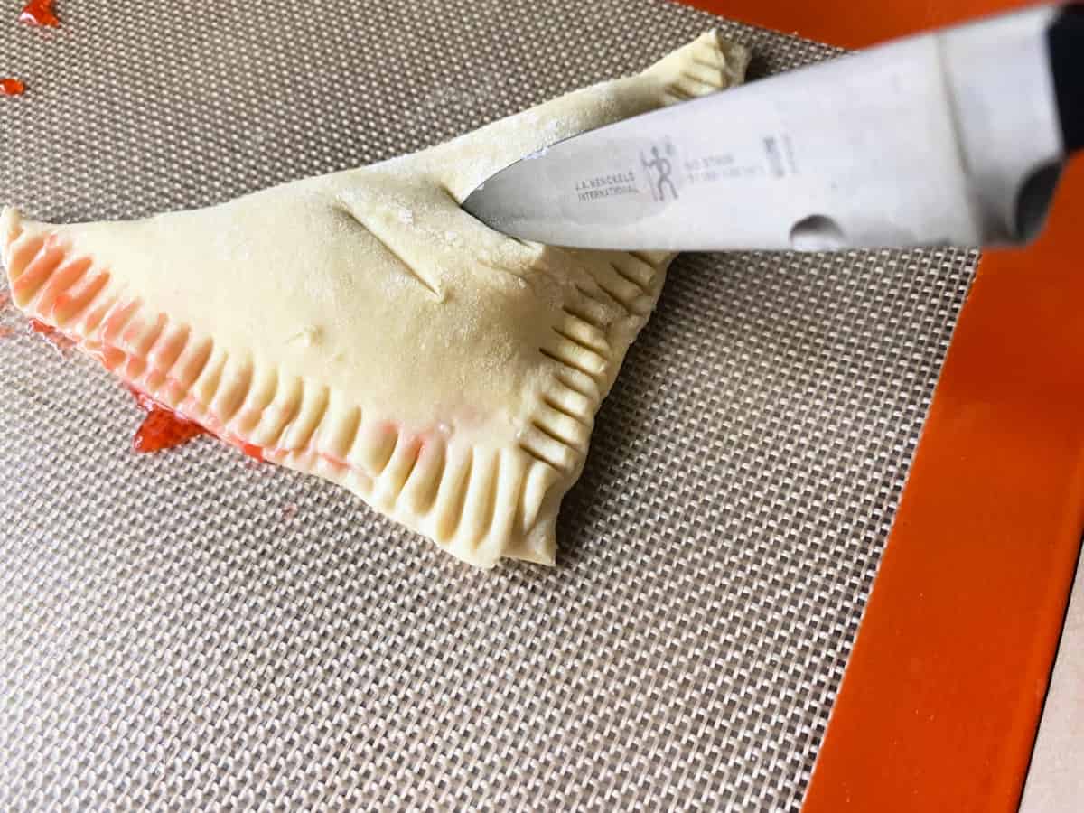 knife making slits in puff pastry triangle.