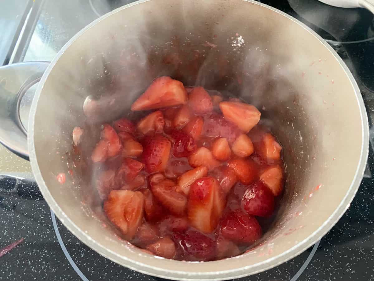 Strawberry glaze in a brown pot on the stove top.