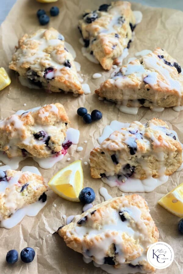 Baked blueberry scones with glaze and fresh blueberries and lemons around them with logo on bottom right corner?