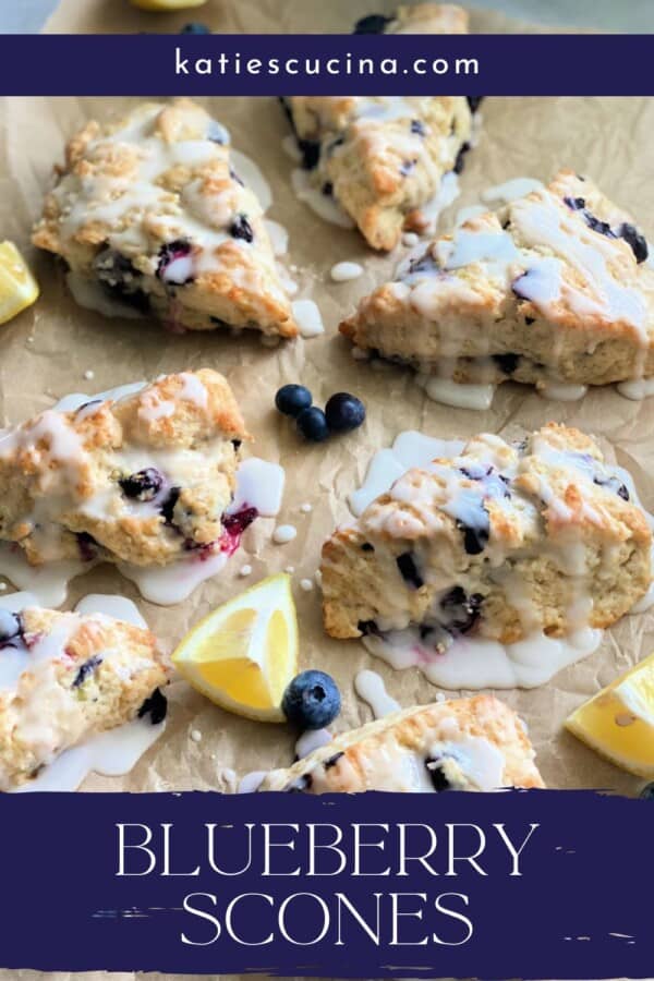 Baked blueberry scones with glaze and lemon wedges with recipe title text on image for Pinterest.