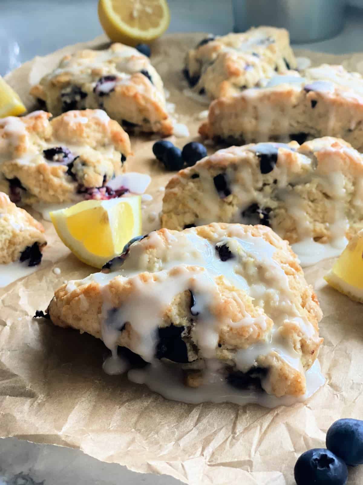 Baked blueberry scones on brown paper with glaze.