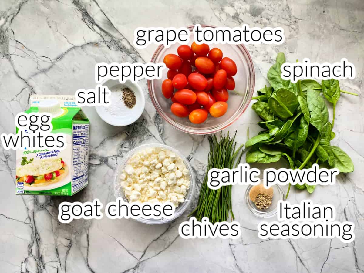 Ingredients on counter: egg whites, tomatoes, pepper, salt, goat cheese, chives, garlic powder, Italian easoning and spinach.
