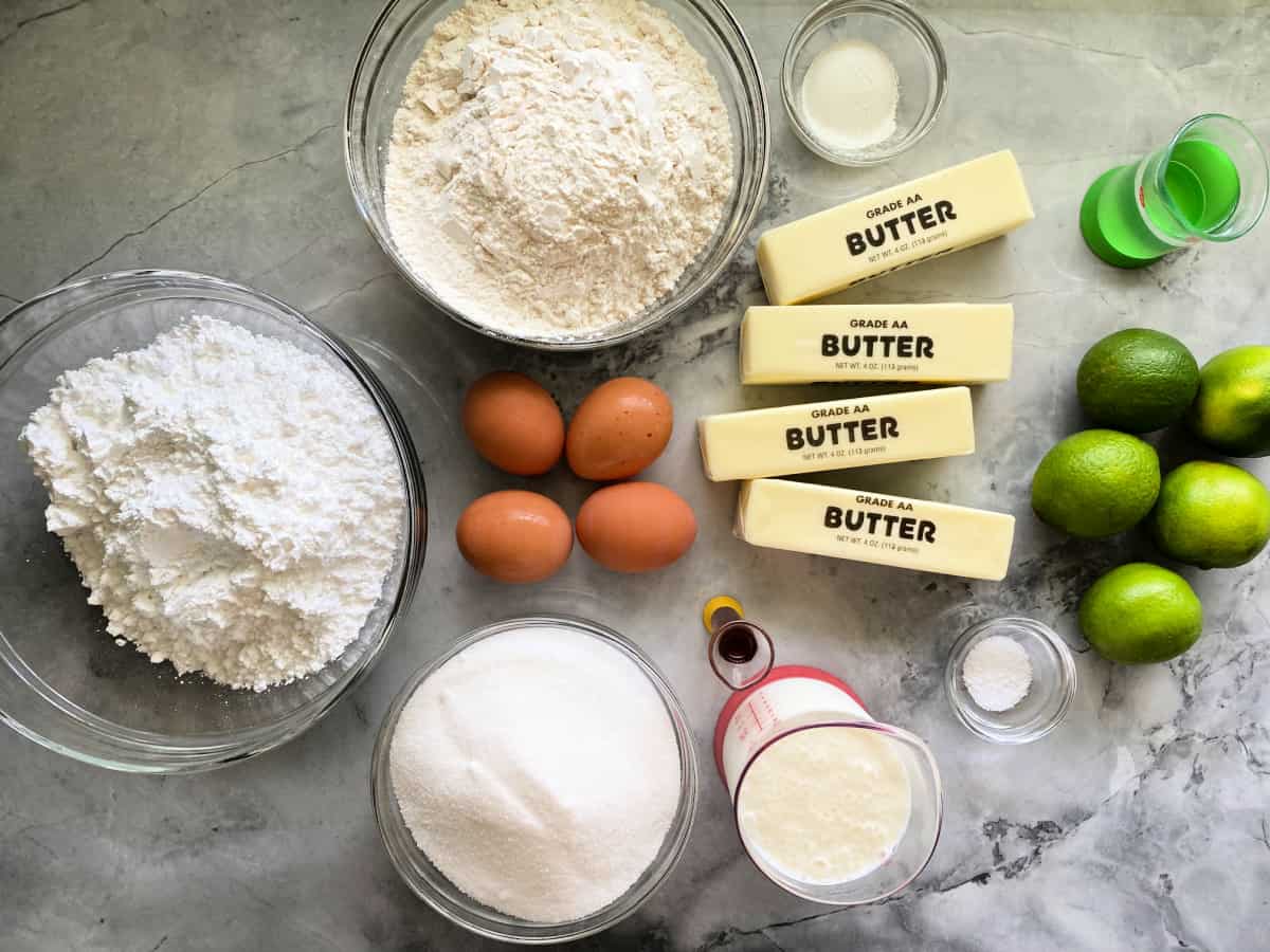 Ingredients on counter; 4 butter sticks, 4 eggs, 5 lime, sugar, flour, oil, buttermilk, salt, vanilla extract.