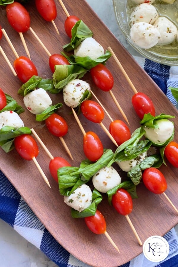 Brown platter filled with Caprese Skewer with logo on right corner.