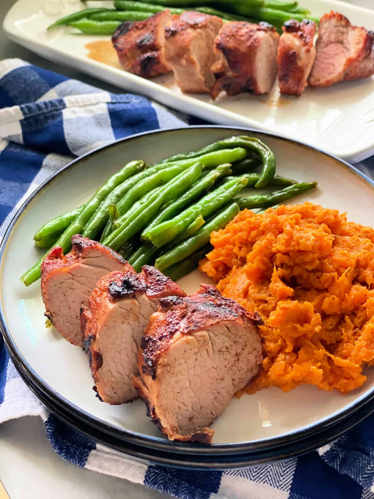 Plate with three slices of pork, green beans, and sweet potatoes.