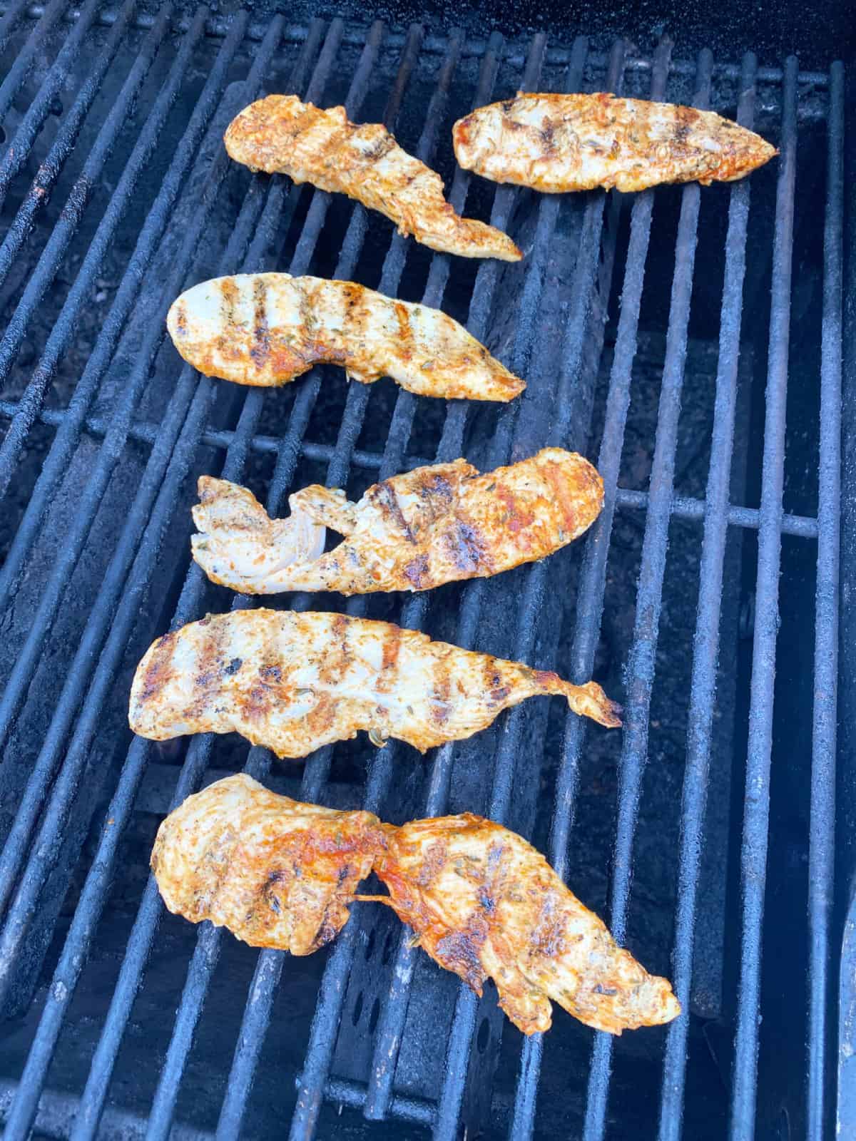 Chicken strips cooked on the grill with grill marks.