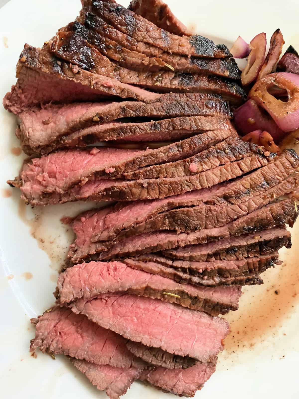 Sliced medium-rare steak on a white plate.