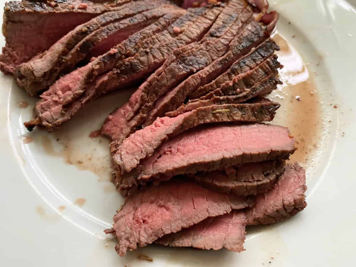 Thin slices of rare steak on a white plate.