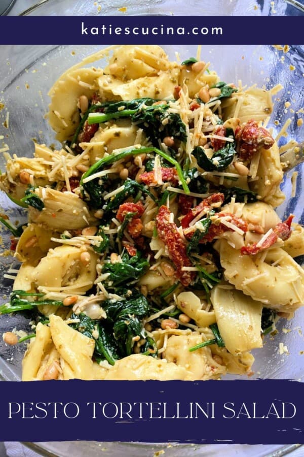 Glass bowl filled with tortellini salad with spinach, tomatoes, pine nuts, and cheese with recipe title text on image for Pinterest.