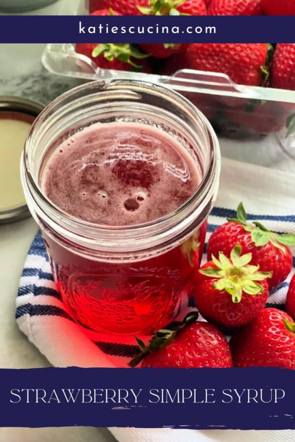 Pink liquid in a glass mason jar surrounded by fresh strawberries with recipe title text on image for pinterest.