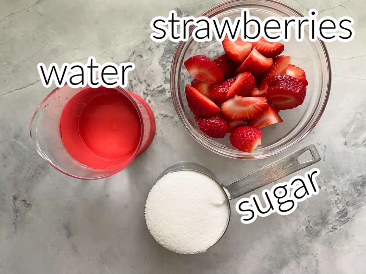 Ingredients on gray and white marble counter: Strawberries, water, and white sugar.