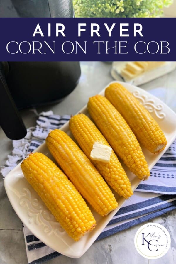 Text on image: "air fryer corn on the cob" with photo of 5 corn on the cobs on a long white dish with a pad of butter on top with a black air fryer and slices of butter on the side