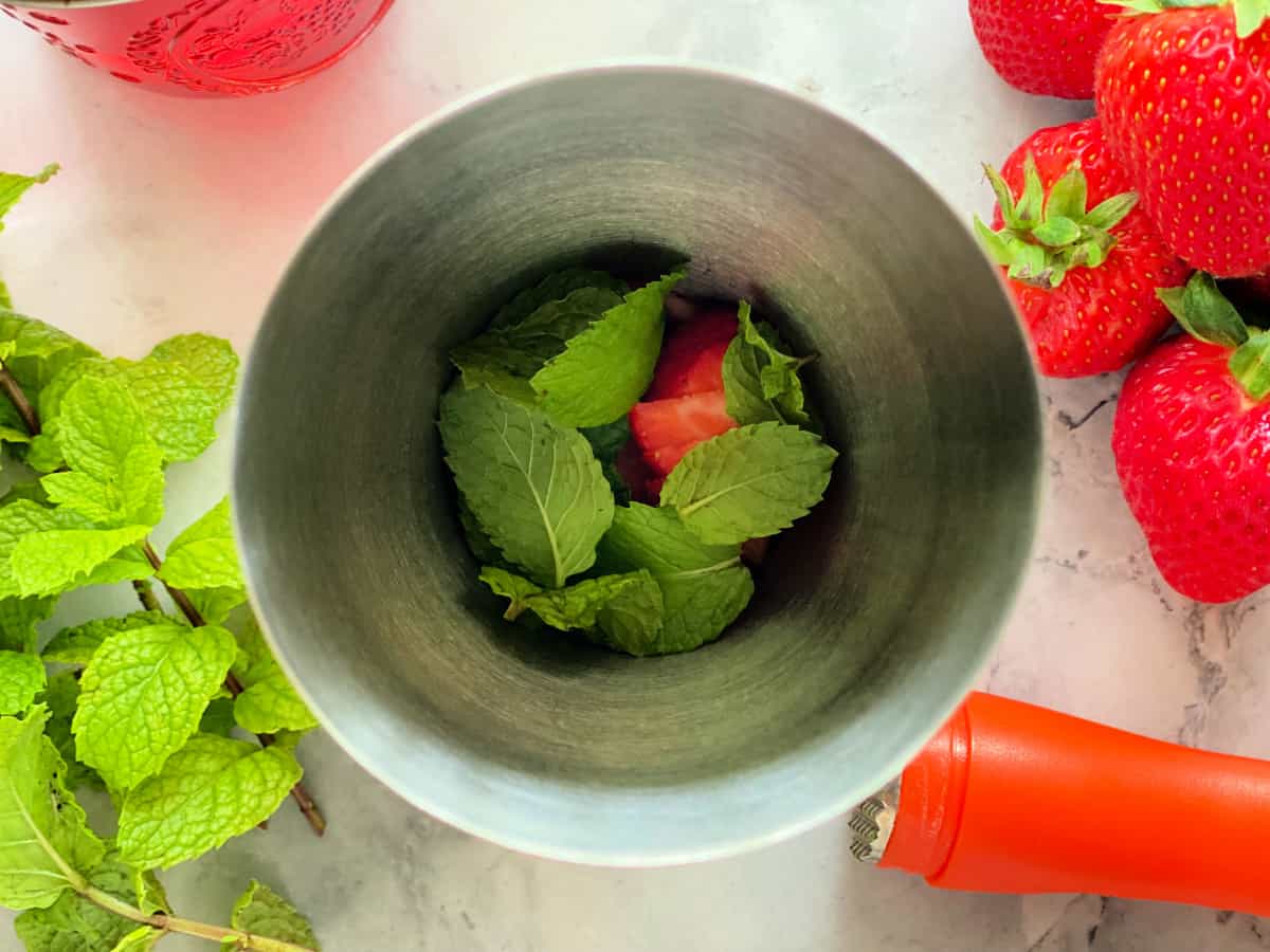 Metal shaker with mint and strawberries.