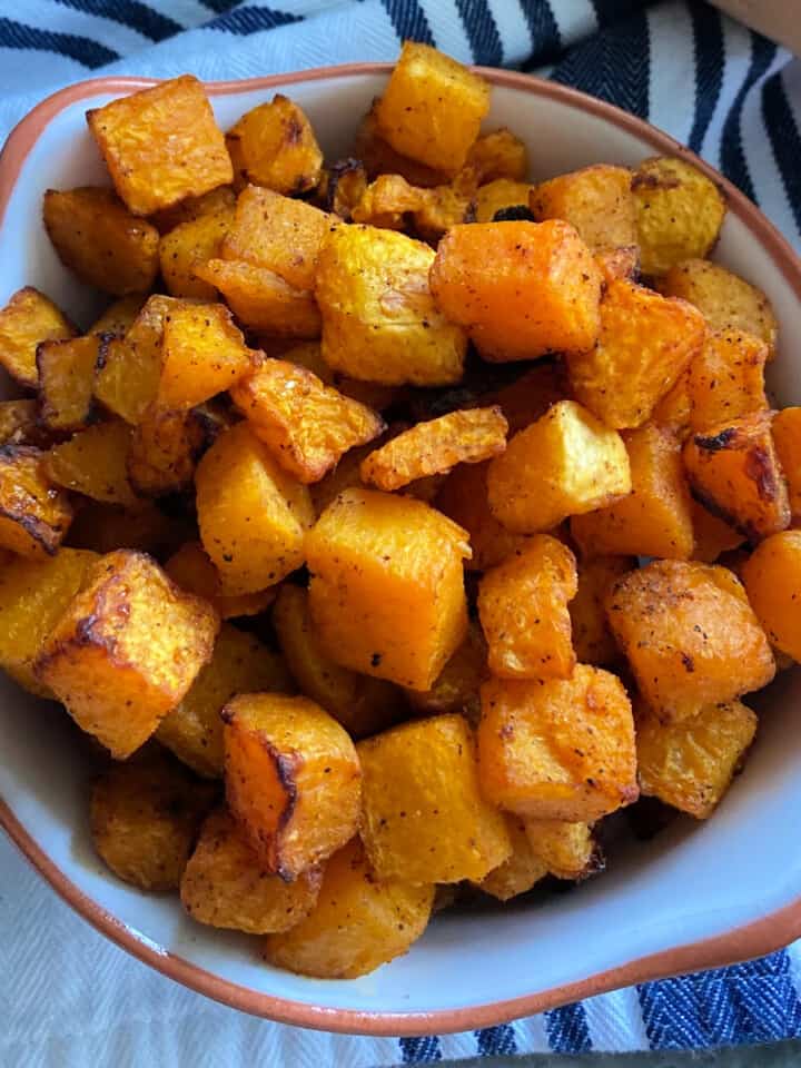 Air fryer butternut squash in a dish on a blue and white striped cloth.