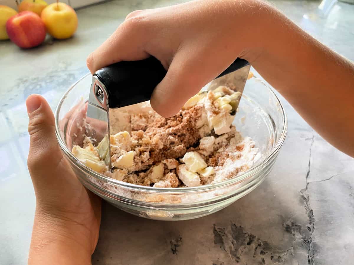 Clear bowl with cinnamon crumb topping ingredients being mashed.