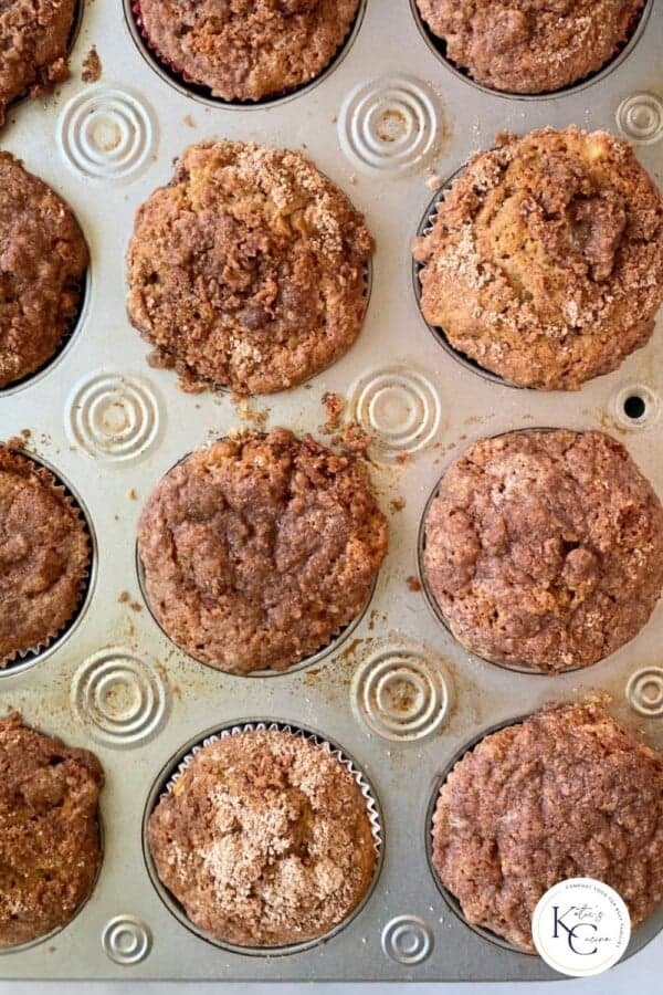 12 baked apple cinnamon muffins in a cupcake pan.