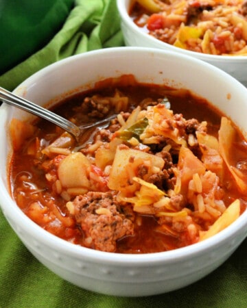close up of bowl with stuffed cabbage soup and a spoon.