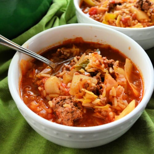 close up of bowl with stuffed cabbage soup and a spoon.