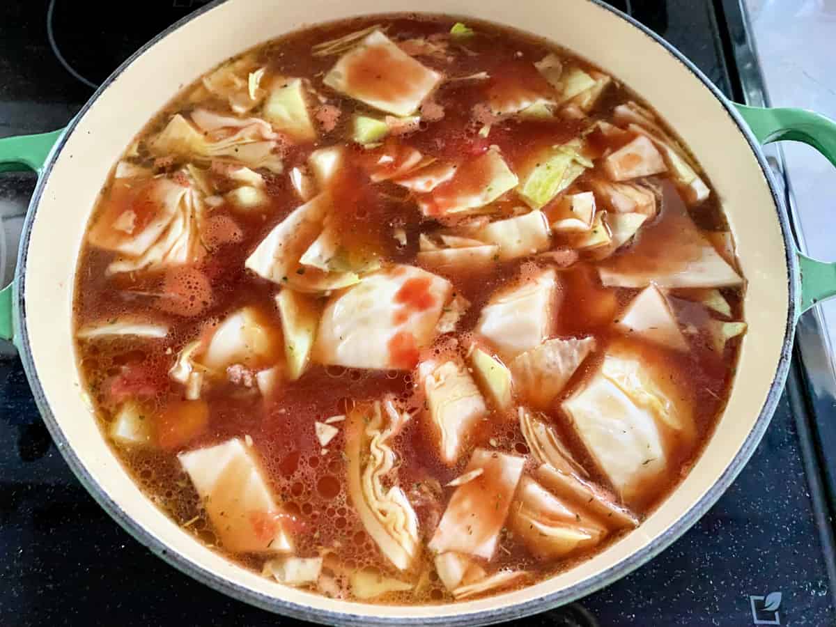 Pot on the stove filled with ingredients for stuffed cabbage soup and broth