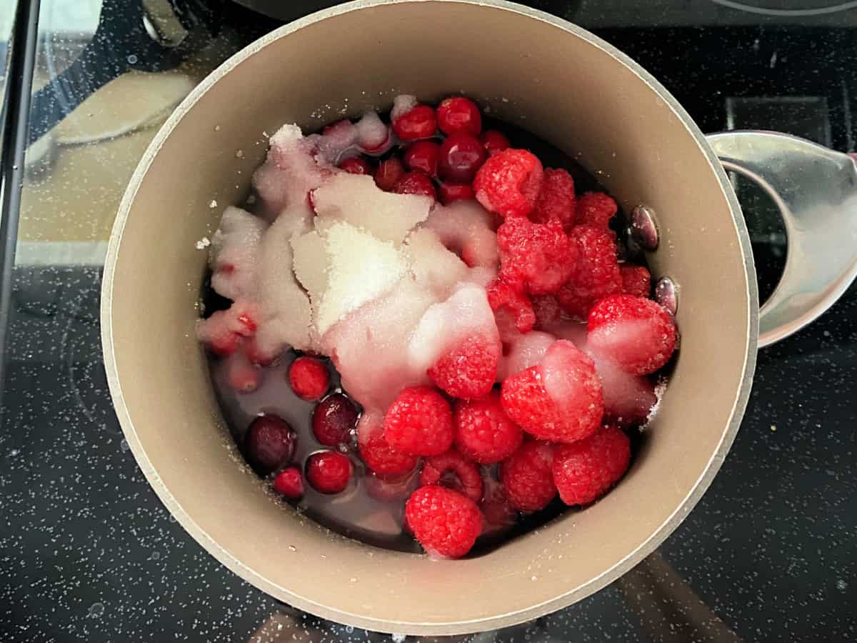 cranberries, raspberries, and sugar in a pot.