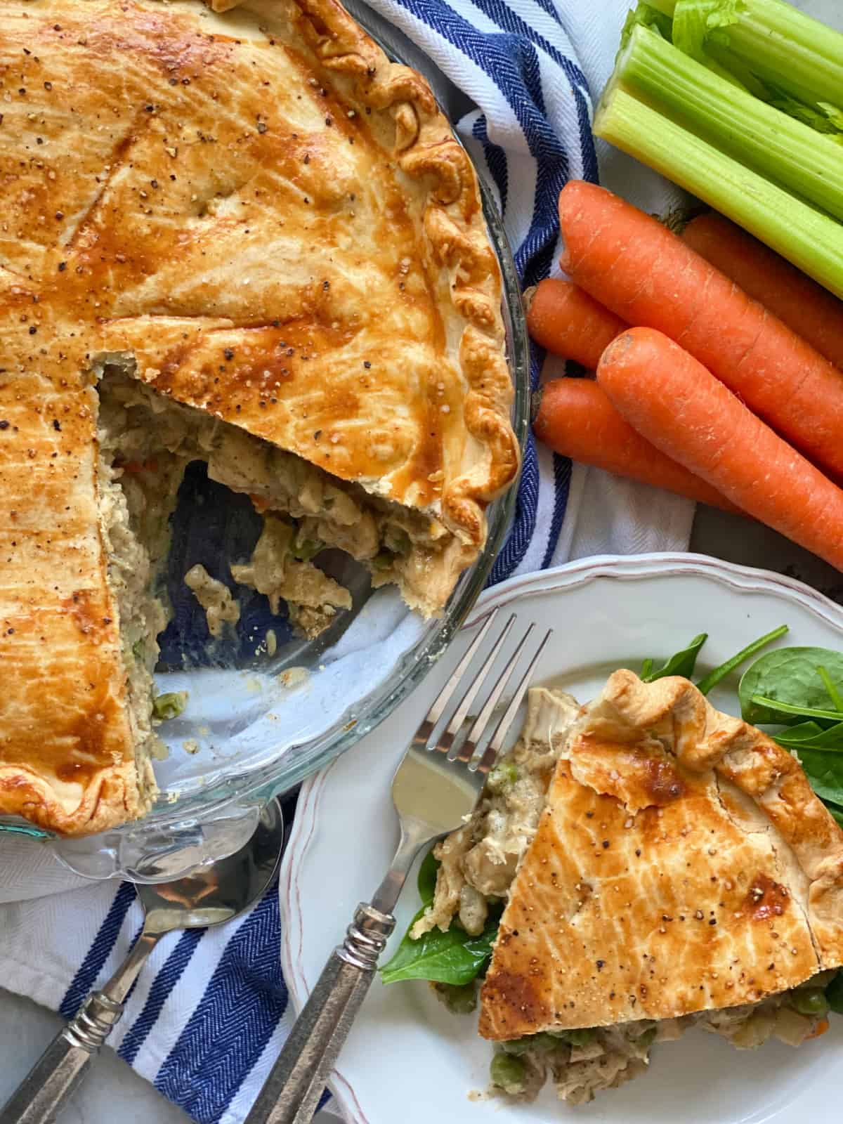 Baked pie with a slice removed and sitting on a white plate with a fork.