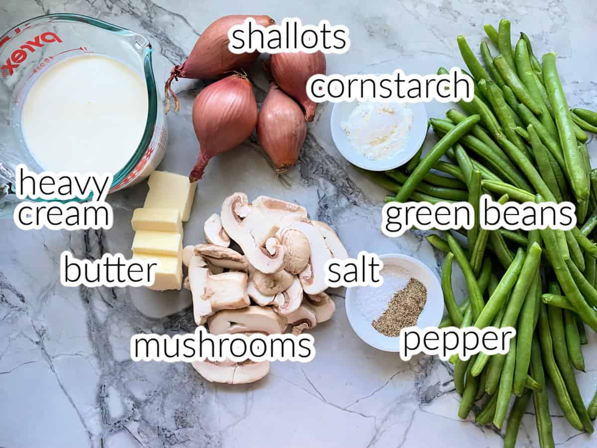 Ingredients on marble counter: heavy cream, butter, mushrooms, shallots, cornstarch, salt, pepper, green beans.