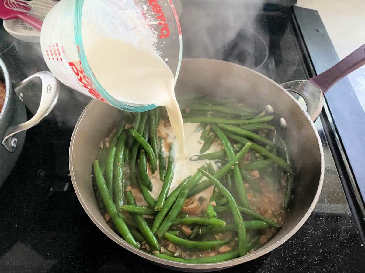 Pan on the stove with green beans and heavy cream.