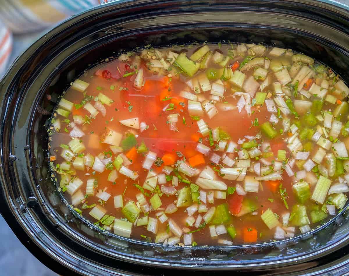 Slow cooker with filled with ingredients and chicken broth.