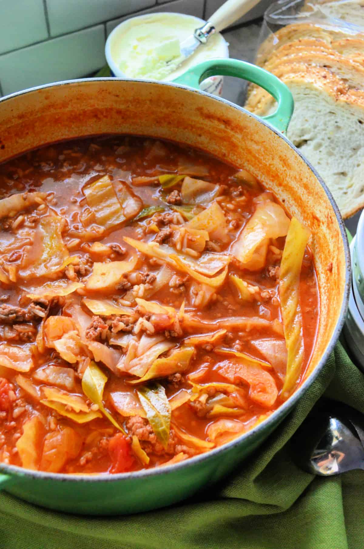 pot of stuffed cabbage soup with slices of bread in the background