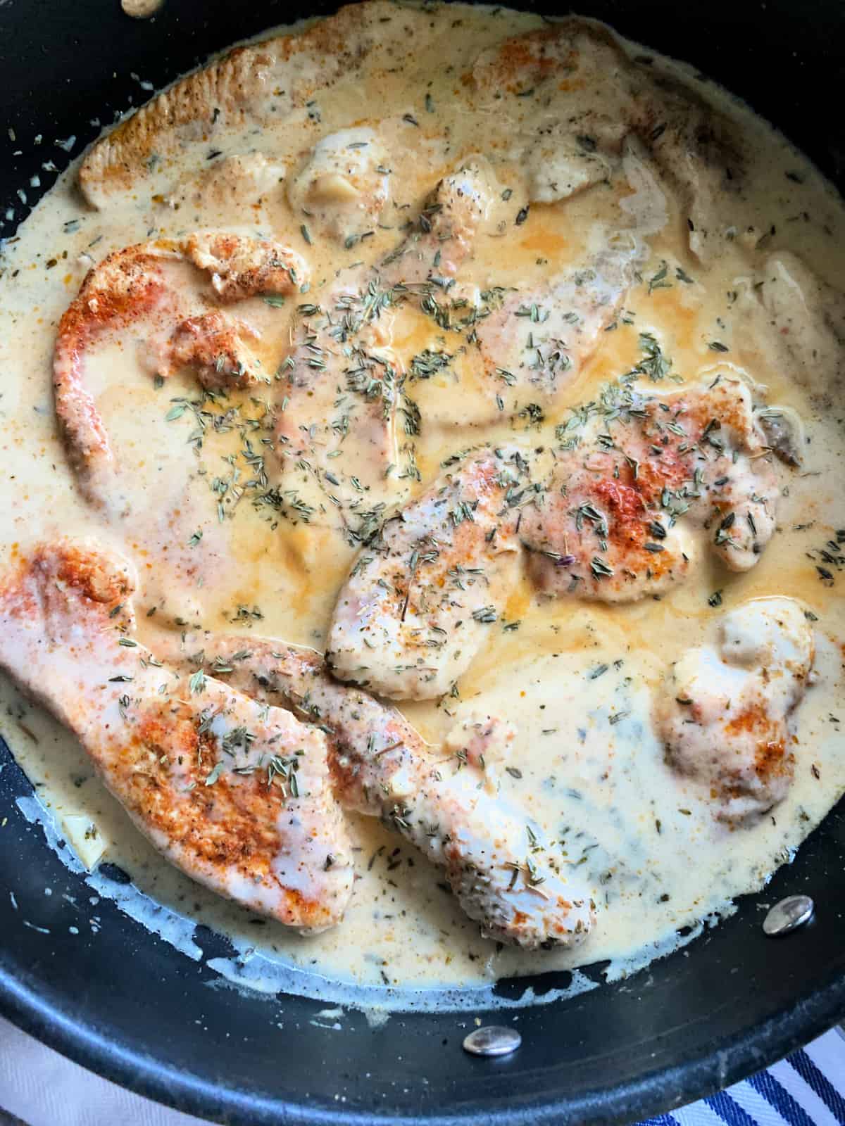 Turkey breast cutlets with a cream sauce in a pan.