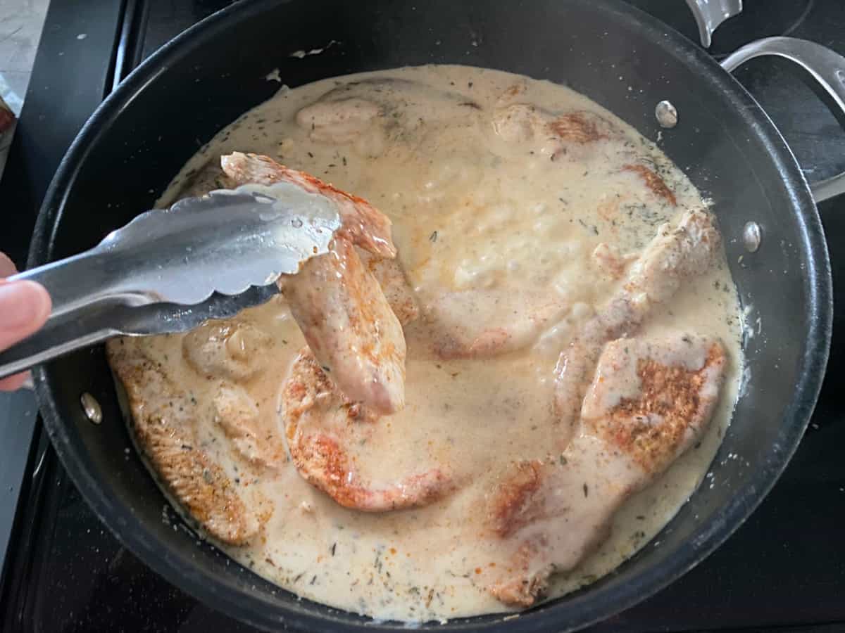 cooked turkey cutlets in a cream sauce on a pan.