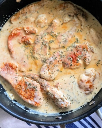 Turkey breast cutlets with a cream sauce in a pan.