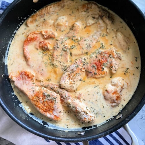 Turkey breast cutlets with a cream sauce in a pan.