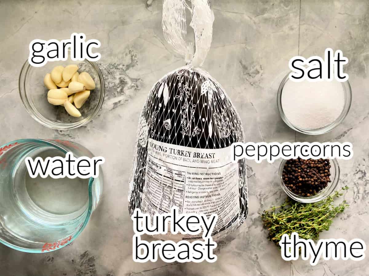 Ingredients on marble counter; turkey breast, water, garlic, salt, peppercorns, and thyme.