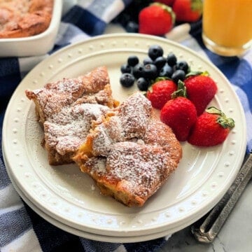 White plate with two pieces of baked french toast with berries.