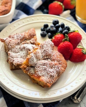 White plate with two pieces of baked french toast with berries.