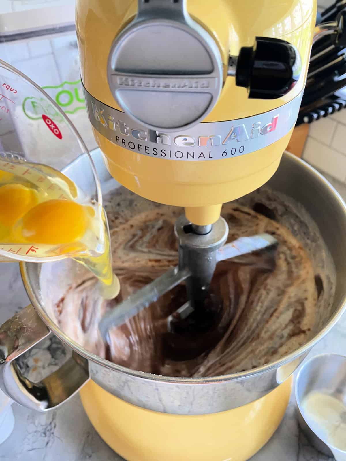 Chocolate cake ingredients being mixed with eggs being added.