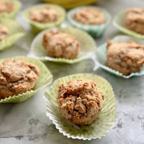 muffins on a marble countertop sitting on top of their wrappers.