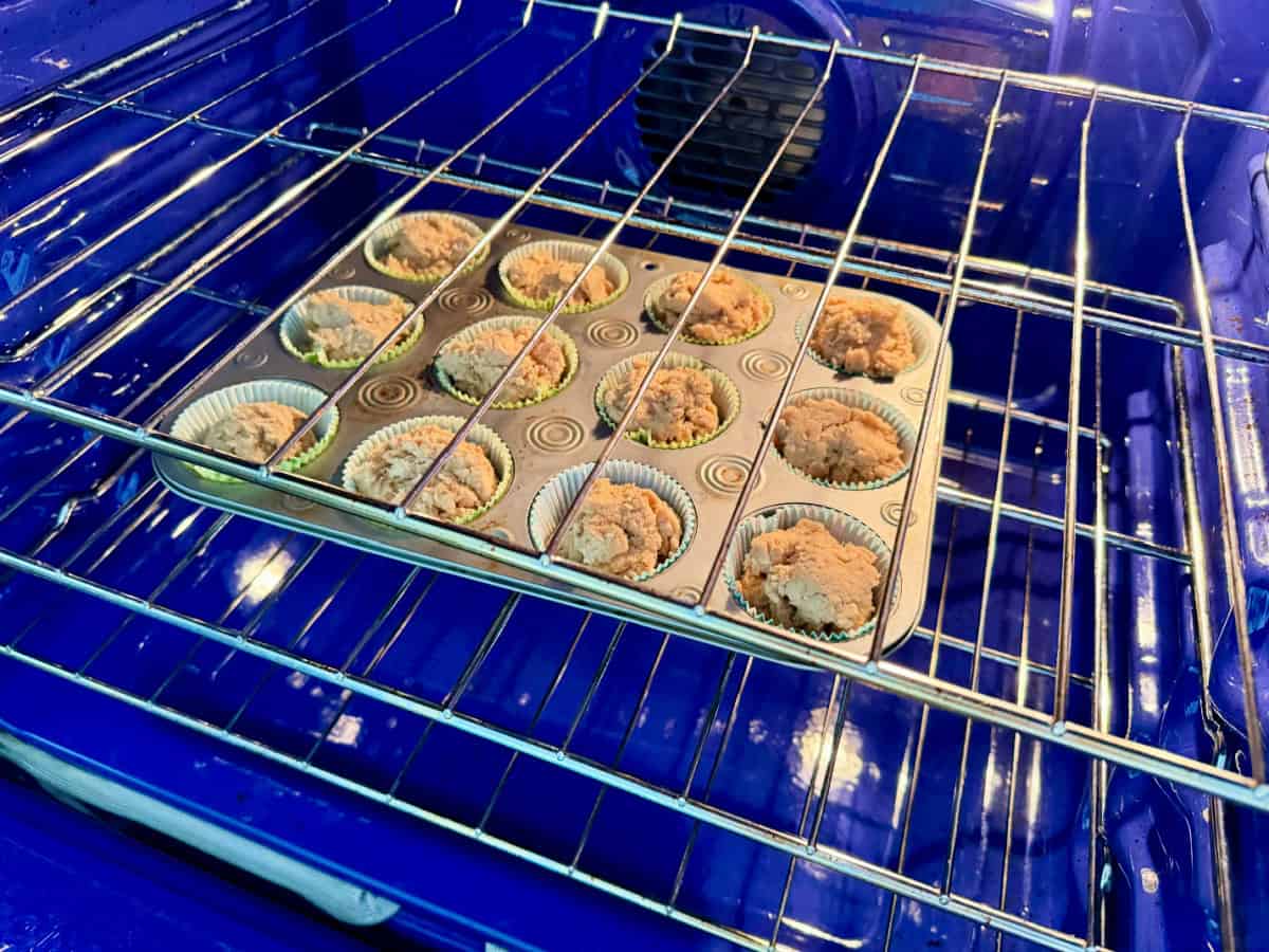12 count muffin tray filled with batter inside a blue oven.